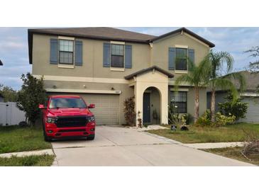 Charming two-story home with a well-maintained lawn and a driveway, accompanied by palm trees in the front yard at 14825 Crescent Rock Dr, Wimauma, FL 33598