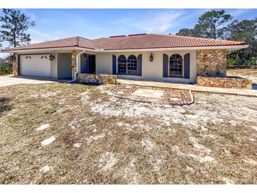 Charming single-story home with a stone-accented facade, terracotta roof, and attached two-car garage at 7281 Jasbow Jct, Weeki Wachee, FL 34613