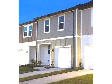 Exterior view of a two-story townhome featuring a gray facade and a one-car garage at 11856 Throttle Pl, Gibsonton, FL 33534