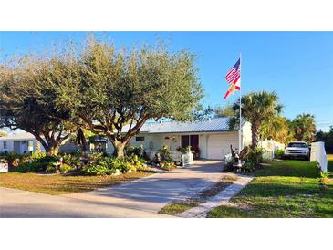 Charming single-story home featuring lush landscaping, mature trees, and a white picket fence at 18671 Kerrville Cir, Port Charlotte, FL 33948