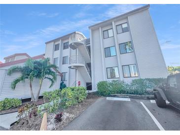 Exterior of a multi-story condominium building with a staircase and lush landscaping around the property at 557 Pinellas Bayway S # 111, St Petersburg, FL 33715