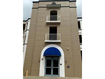 Exterior shot of a multi-story condo building with balconies and a blue awning over the entrance at 8111 Lakewood Main St # 207, Lakewood Ranch, FL 34202