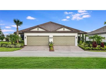 Charming villa exterior featuring a brick driveway, two-car garage, manicured lawn, and tile roof at 6233 Plateau Ct, Bradenton, FL 34203