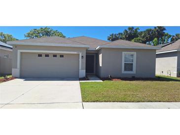 Charming single-story home featuring a well-maintained lawn and an attached two-car garage at 10417 Candleberry Woods Ln, Gibsonton, FL 33534