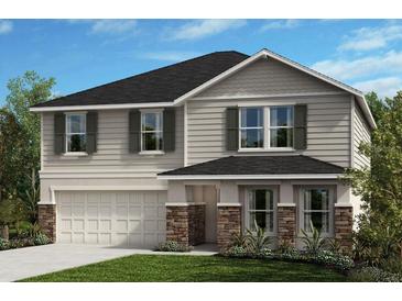 Charming two-story home with a manicured lawn, covered entrance, attached garage, and beautiful landscaping at 10955 Bluestem Cv, Parrish, FL 34219