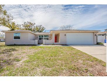 Charming single-story home featuring an attached garage, red front door, and a well-maintained lawn at 9811 Rainbow Ln, Port Richey, FL 34668