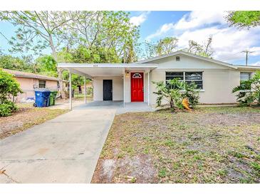 Charming single-story home with a red front door, carport, and well-lit entry, creating a warm, inviting curb appeal at 4218 E Paris St, Tampa, FL 33610
