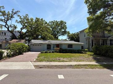 Charming single-story home with a brick driveway and mature landscaping at 4906 W Cleveland St, Tampa, FL 33609