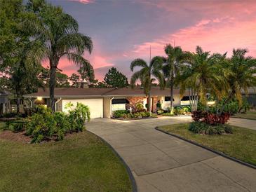 Charming single-story home features lush tropical landscaping and a wide driveway leading to an attached garage at 650 Poinsettia Rd, Belleair, FL 33756