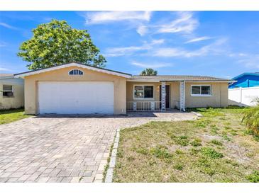 Charming single-story home featuring an attached garage, brick driveway, and a well-maintained front lawn at 10105 Vineyard Ln, Port Richey, FL 34668