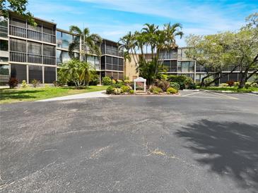 Exterior view of the condo building showcasing landscaping, palm trees, and well-maintained grounds at 612 Bird Bay S Dr # 113, Venice, FL 34285
