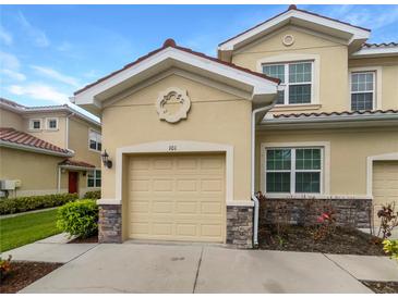 Charming townhome featuring an attached garage, neutral stucco and stone accents, and a red-tile roof at 8110 Enclave Way # 101, Sarasota, FL 34243