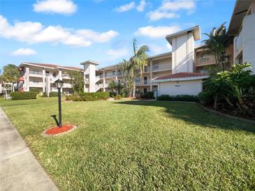 Multi-story condo building with lush landscaping and well-maintained lawn under a bright blue sky at 6507 Stone River Rd # 310, Bradenton, FL 34203