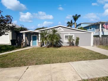 Charming single-story home with a well-maintained lawn, cute landscaping, and a bright blue front door at 141 81St N Ave, St Petersburg, FL 33702