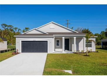 Charming single-story home with a well-manicured lawn, a dark gray garage door, and neutral color palette at 25372 Alicante Dr, Punta Gorda, FL 33955