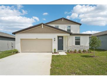 Charming two-story home featuring a 2-car garage, stone accents, and a well-manicured lawn at 31653 Wild Grape Ln, Brooksville, FL 34602