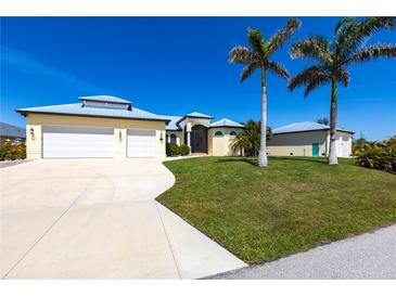 Beautiful home with a three-car garage, metal roof, and lush landscaping featuring palm trees under a bright blue sky at 3215 Peace River Dr, Punta Gorda, FL 33983