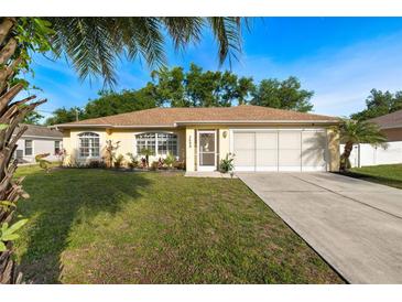 Charming single-story home with a well-maintained lawn, landscaped garden, and a two-car garage at 3699 N Chamberlain Blvd, North Port, FL 34286