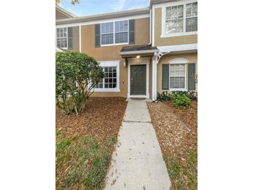 Charming tan two-story townhome with a well-manicured lawn and a welcoming entryway at 1238 Standridge Dr, Wesley Chapel, FL 33543