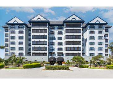 Stunning exterior of a multi-story white condo building with lush landscaping and a circular driveway leading to a covered entrance at 14810 Rue De Bayonne # 7B, Clearwater, FL 33762