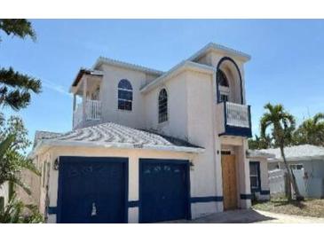 Stunning two-story home with blue accents, arched windows, and a well-manicured lawn at 11120 5Th E St, Treasure Island, FL 33706