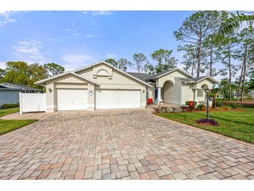 Charming single-story home featuring a brick driveway, three-car garage and lush landscaping at 2444 Grandfather Mtn, Spring Hill, FL 34606