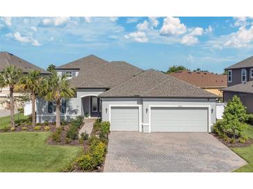 Charming single-Gathering home featuring a three-car garage, brick driveway, and manicured landscaping at 32554 Silvercreek Way, Wesley Chapel, FL 33545