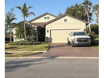 Charming single-story home with a two-car garage, brick driveway, landscaped yard, and palm trees at 1427 Hyssop Loop, North Port, FL 34289