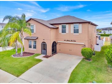 Charming two-story home with a well-maintained lawn, tall palm tree and attached two car garage at 10607 Standing Stone Drive, Wimauma, FL 33598