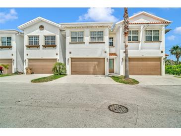 Inviting townhome exterior showcasing attached garages, manicured lawns and a well-maintained white facade at 8614 Miramar Terrace Cir, Temple Terrace, FL 33637