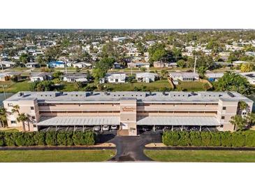 Exterior full view of tan condo building with parking underneath and trimmed hedges in a community at 2486 Caring Way # 17A, Port Charlotte, FL 33952