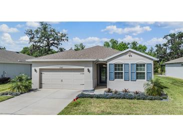 Charming single-story home with a well-manicured lawn and blue shutters, showcasing its inviting curb appeal at 12387 Eastpointe Dr, Dade City, FL 33525