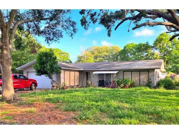 Charming single-story home featuring a well-kept lawn and vibrant landscaping, enhanced by mature trees and sunny skies at 1420 Citrus St, Clearwater, FL 33756