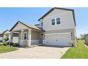 Charming two-story home with covered porch, brick accents, manicured lawn, and an attached two car garage at 1878 Draughton Dr, Zephyrhills, FL 33541