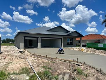 New construction home features a metal roof, gray stucco exterior, and a freshly poured concrete driveway at 24462 Cabana Rd, Punta Gorda, FL 33955