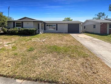 Charming single-story home with a well-maintained lawn and attached garage on a sunny day at 9210 Crabtree Ln, Port Richey, FL 34668