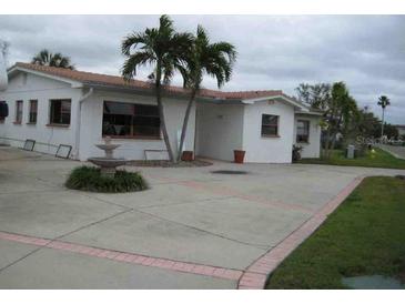 Charming single-story home featuring a spacious driveway, stucco siding, and mature palm trees at 17401 1St E St, Redington Shores, FL 33708