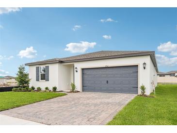 Charming single-story home with a paved driveway, well-maintained lawn, and a gray two-car garage door at 1752 Brekey Way, Zephyrhills, FL 33541
