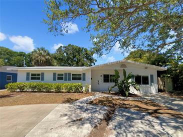 Charming single-story home featuring a well-manicured lawn, beautiful landscaping, and a concrete driveway at 4825 W Bay Court Ave, Tampa, FL 33611