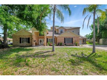 Two-story home with brick and siding exterior, complemented by palm trees and a well-manicured lawn at 20003 Holly Lake Pl, Lutz, FL 33558