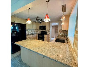 Well-lit kitchen featuring granite countertops, stainless steel appliances, and unique hanging pendant lights at 5428 Nutmeg Ave, Sarasota, FL 34231