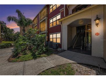 Inviting exterior view showcasing a red condominium building with lush landscaping and architectural details at 11901 4Th N St # 2107, St Petersburg, FL 33716