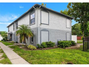 Two-story condo features a combination brick and stucco facade, a small palm tree, and manicured shrubs at 5112 Temple Heights Rd # B, Tampa, FL 33617