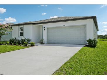 Charming single-story home with a well-maintained lawn, a two-car garage, and lush landscaping at 7740 Gilchrist Springs Dr, Parrish, FL 34219