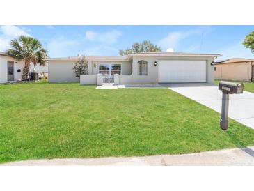 Charming single-story home with a well-manicured lawn and a two-car garage on a sunny day at 8506 Moulton Dr, Port Richey, FL 34668