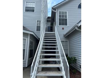 Exterior of home showing staircase leading to the entrance of the home, with light gray siding at 12219 Armenia Gables Cir, Tampa, FL 33612
