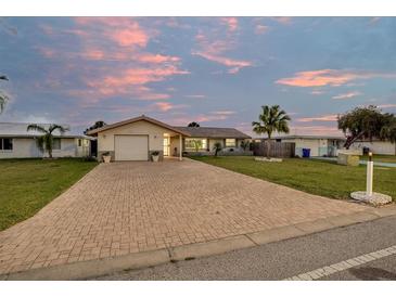 Charming single-story home with a brick driveway and well-maintained front yard, set against a beautiful sunset sky at 4043 Topsail Trl, New Port Richey, FL 34652