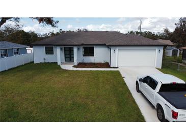 Charming single-story home with a well-manicured lawn, attached garage, and modern front door at 20296 Rutherford Ave, Port Charlotte, FL 33952