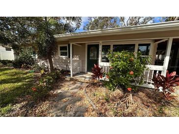 Charming single-story home featuring a cozy front porch and lush tropical landscaping at 3141 Irving St, Sarasota, FL 34237