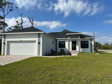 Modern home featuring a two-car garage, manicured lawn, and stylish architectural details on a sunny day at 15561 Aldama Cir, Port Charlotte, FL 33981